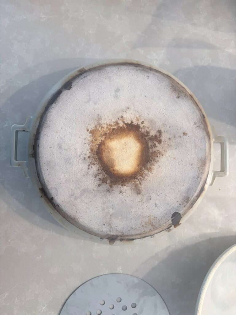 The unglazed base of a donabe, scorched from two winters on a gas flame