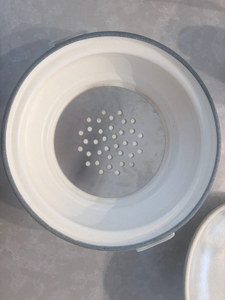 A perforated aluminium disc sitting in the base of a donabe