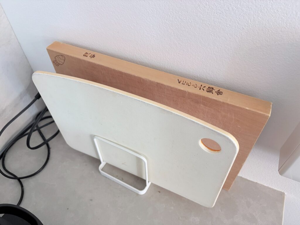 Japanese cutting board stored on edge next to a plastic one