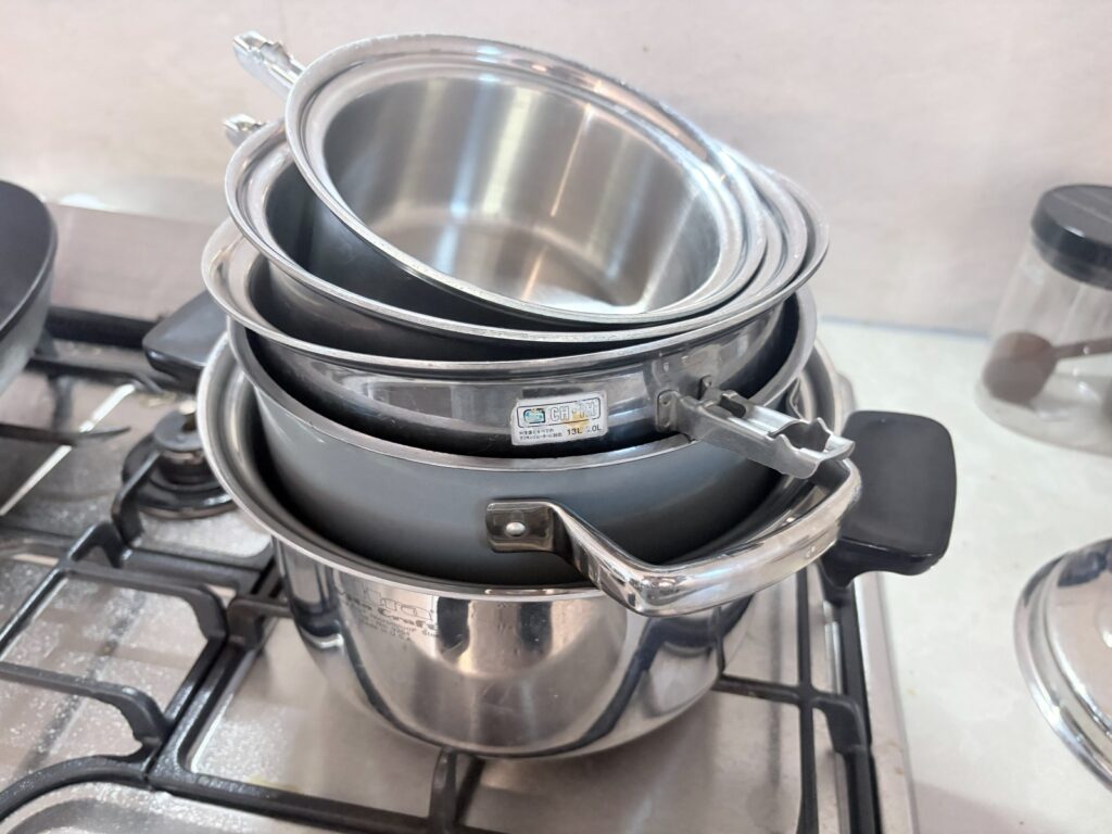 The same stack with a fixed-handle German casserole nested inside it, its handle projecting